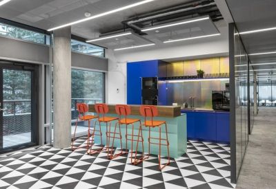 Modern office kitchen featuring blue cabinetry and a checkerboard floor.