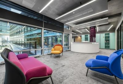 Lounge area with colorful purple and blue armchairs and a white reception desk.