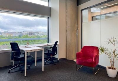 Bright office space featuring a white desk and a stylish red velvet armchair.