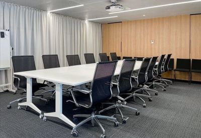 Large professional boardroom with a long white table, ergonomic chairs, and wood-paneled walls.