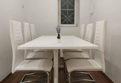 Private meeting room with a long white table and elegant white chairs.