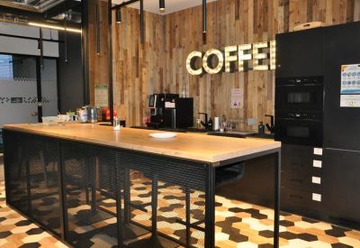 Kitchenette area with a coffee station, wood-paneled walls, and a large neon coffee sign.