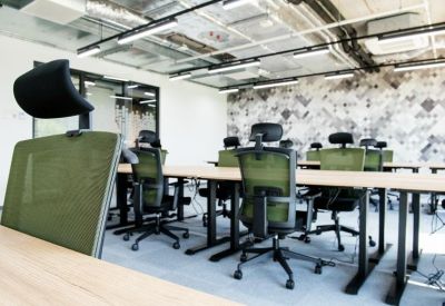 Open-plan coworking area with green mesh chairs and wood-tone desks.