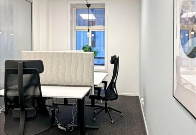 Bright workspace featuring two modern black ergonomic chairs and a white desk with a divider.