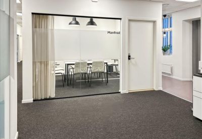 Professional meeting room with a glass wall overlooking a table with white chairs and pendant lights.