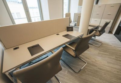 Co-working space with long white desks and leather swivel chairs.