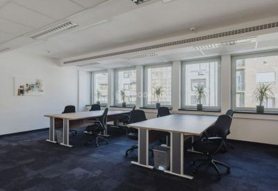 Open-plan office with multiple workstations, ergonomic chairs, and large windows.