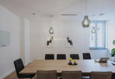 Professional meeting room with a wooden table, black chairs, and stylish pendant lighting.