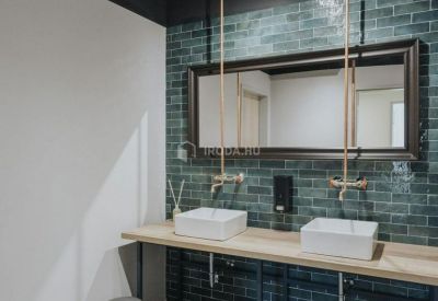 Modern restroom featuring dual square vessel sinks, brass fixtures, and teal brick tiling.
