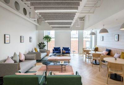 Spacious lounge area with gray sofas, blue armchairs, and colorful geometric rugs.