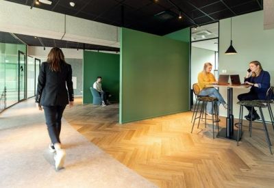 Coworking lounge area with green feature walls and herringbone wood flooring.
