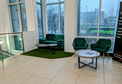 Communal breakout area featuring green velvet chairs and a faux-grass rug.