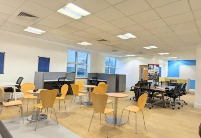 Bright coworking space with yellow dining chairs and private work booths.