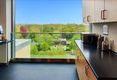 Modern kitchenette area with coffee machine and scenic green views.