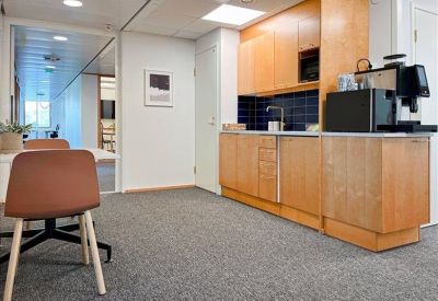 Office kitchen area with light wood cabinetry and a coffee machine.