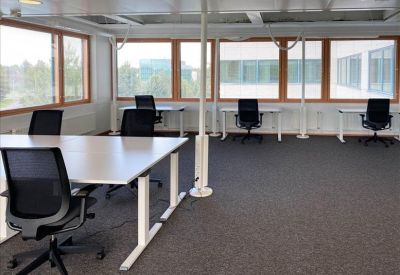 Spacious open-plan office with white desks and black ergonomic chairs.