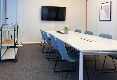 Bright conference room with a long white table and blue chairs.