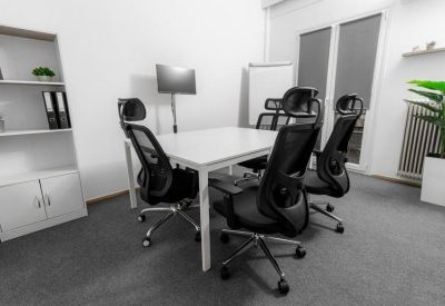 Four-person white meeting table with black mesh chairs and a white mobile whiteboard.