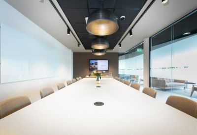 Large boardroom with a long white table and modern pendant lighting.