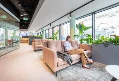 Lounge area with pink velvet sofas, large windows, and indoor greenery.