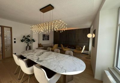 Communal dining area with a marble-top table and a decorative crystalline chandelier.