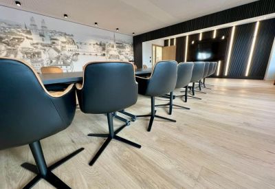 Meeting room with black swivel chairs, light wood floors, and a large architectural mural.