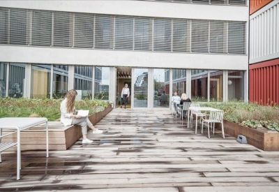 Outdoor wooden terrace with seating and planters beside the office building.