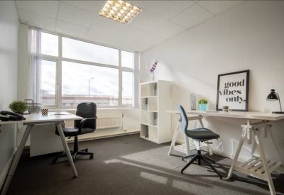 Well-lit private office with a large window, white shelving, and a motivational wall print.