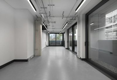 Bright, empty open-plan office space with industrial ceilings and glass partitions.