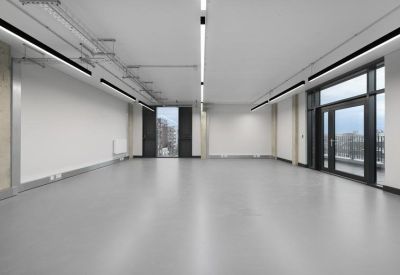 Large, light-filled vacant studio space with polished grey floors and floor-to-ceiling windows.
