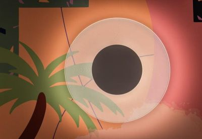 Close-up of a circular wall light casting a soft glow against a sunset-themed mural.