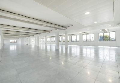 Spacious, empty office floor with rows of windows and white support columns.