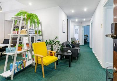 Reception area with a yellow armchair, potted plants, and a white ladder bookshelf.