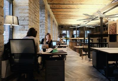 Exposed stone wall workspace with people working at desks under a timber beam ceiling.