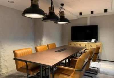 Professional meeting room featuring tan leather chairs and industrial-style pendant lamps.