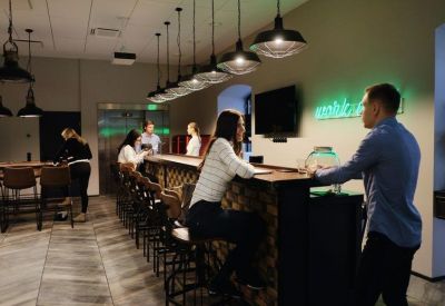 Social cafe area with a high bar counter, pendant lighting, and neon wall signage.