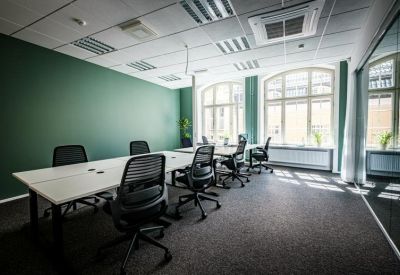 Bright office space with white desks, ergonomic chairs, and a green feature wall.