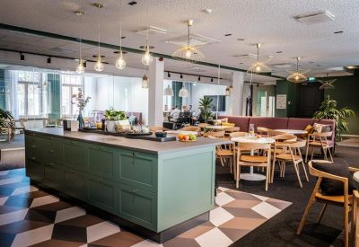 Large communal kitchen and dining area with green cabinetry and geometric floor tiles.