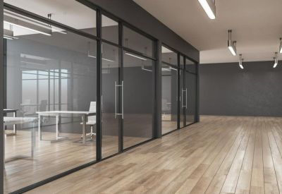 Hallway view of professional glass-partitioned meeting rooms with wooden flooring.