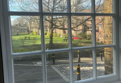 View through a multi-pane window looking onto a green courtyard with picnic benches.