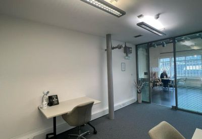 Bright workspace with a desk and glass partition looking into a meeting area.