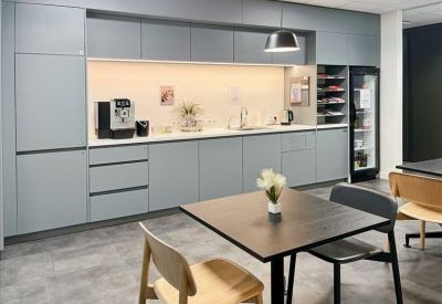 Modern office kitchen with blue cabinetry and a black coffee machine.