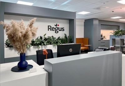 Sleek grey reception desk featuring the Regus logo and indoor plants.