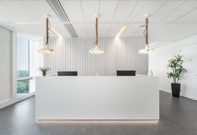 Minimalist white reception desk with three unique industrial pendant lights and potted plants.