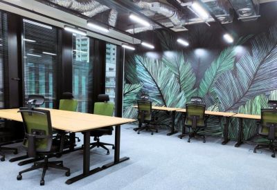 Modern office with workstations and a large tropical leaf mural.