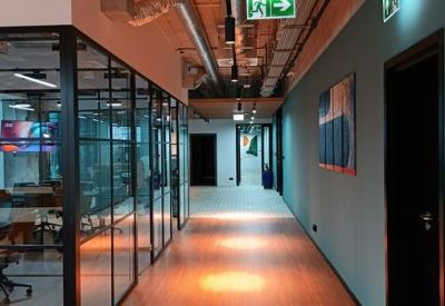 Hallway featuring glass-walled meeting rooms and industrial lighting.