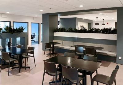 Spacious break area with dark wooden tables, booth seating, and indoor greenery.
