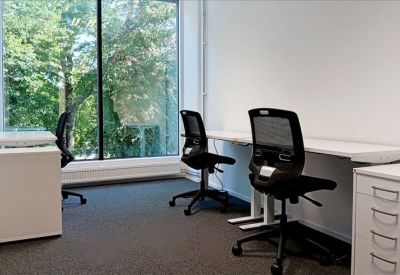 Private office with white desks and views of lush green trees.