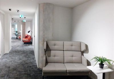 Cozy lounge nook featuring a grey tufted high-back sofa and a small side table with a plant.