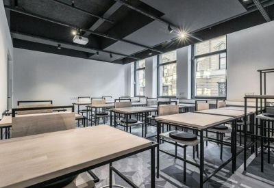 Bright classroom-style meeting room with light wood tables and black industrial ceiling.